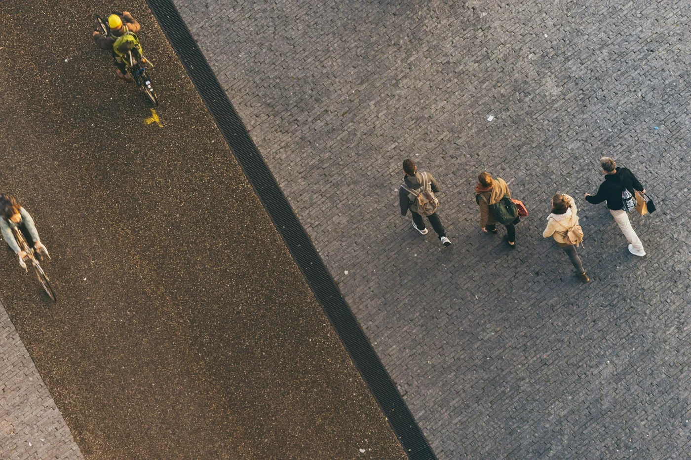 An overhead view of people walking and cycling along a paved street