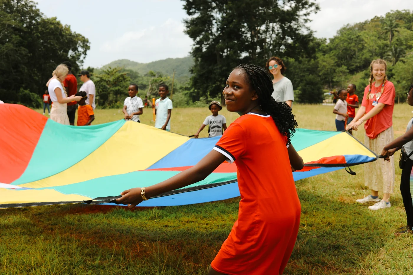 Children and adults playing with a colorful parachute in a grassy field