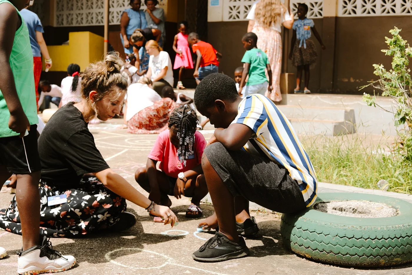 Adults and children drawing with chalk together in an outdoor courtyard