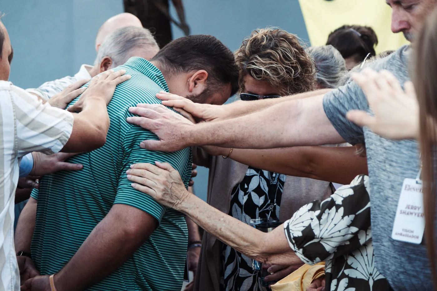 People praying together with hands resting on one another’s shoulders